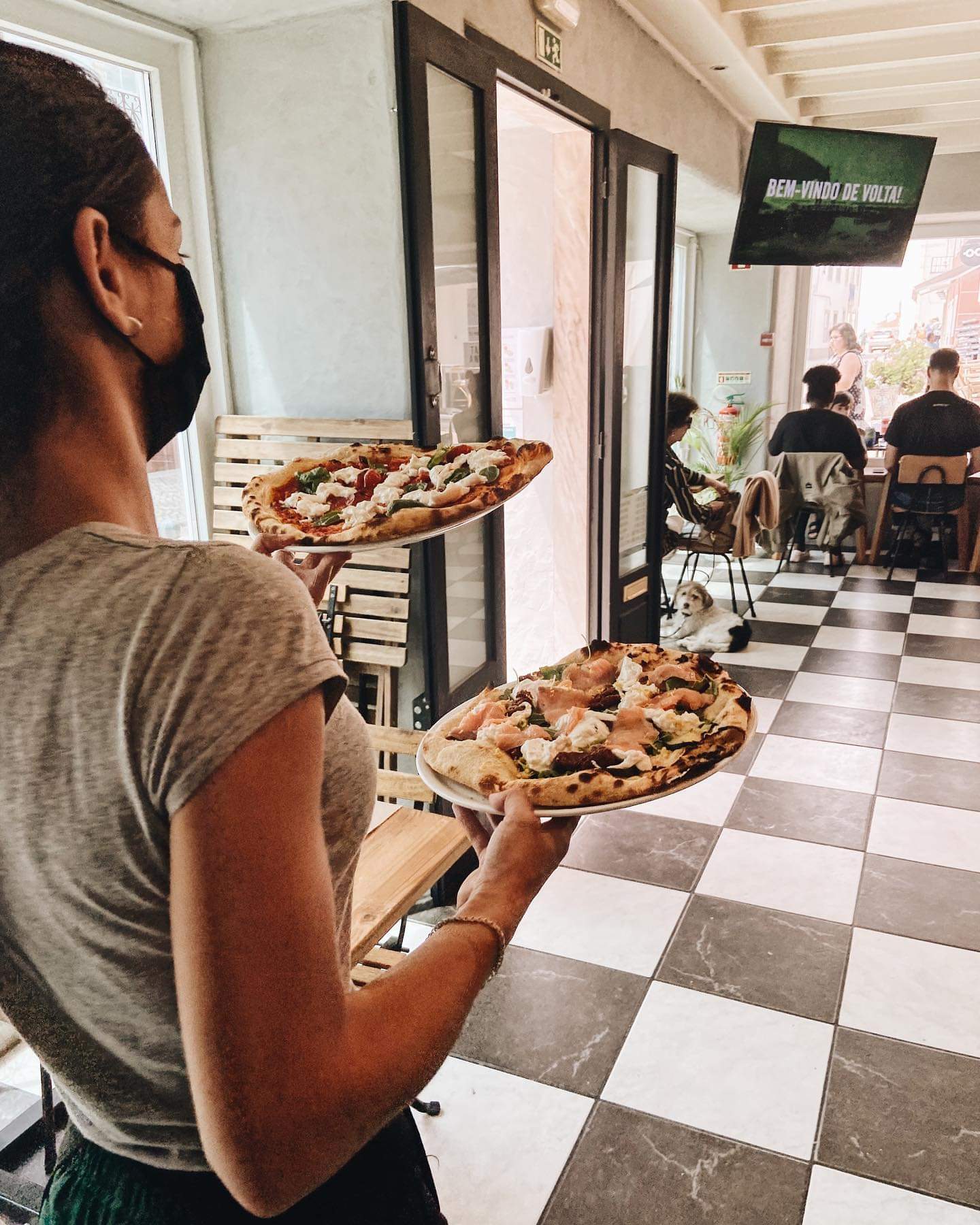 Waitress serving pizzas at pet-friendly restaurant Pepe Verde Pizzeria